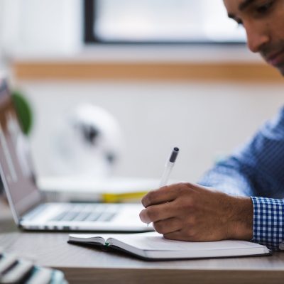 爱给网运营编辑在笔记本前回复读者邮件，桌面摊开字体授权笔记与便签的日常办公场景